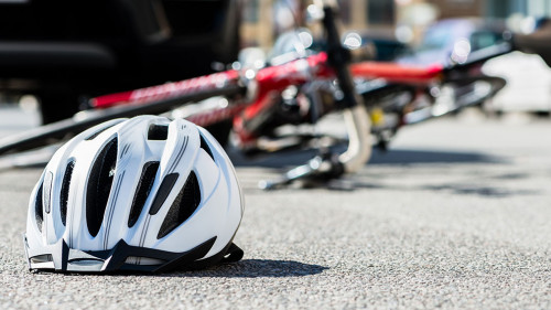Close-up of a bicycling helmet on the asphalt next to a bicycle