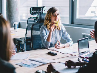 Creative young woman with sticker in hands discussing productive