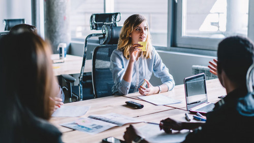 Creative young woman with sticker in hands discussing productive