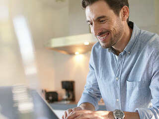Handsome man with computer in modern kitchen