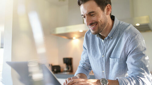 Handsome man with computer in modern kitchen