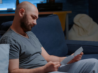 Man open warning document, reading letter from bank about loan refusal