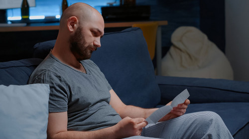 Man open warning document, reading letter from bank about loan refusal
