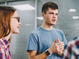 Serious hipster guy explaining study process to male and female