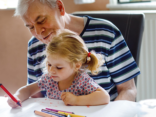 Cute little baby toddler girl and handsome senior grandfather painting with colorful pencils at home. Grandchild and man having fun together