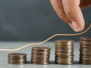 Salary increase concept. Woman stacking coins on grey table and