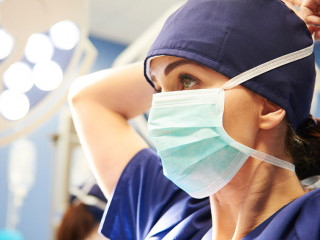 Side view of young female surgeon tying her surgical mask