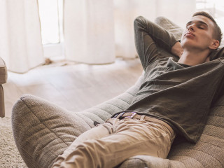 Handsome teenage guy relaxing on modern soft couch at home in li
