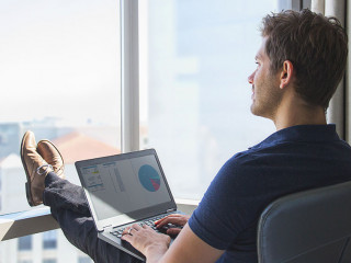 Young businessman in casual attire working on laptop at home off