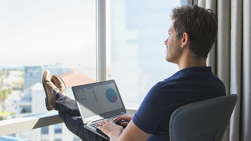 Young businessman in casual attire working on laptop at home off