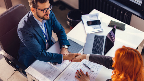Happy bank manager shaking hands with a client after successful agreement in the office.
