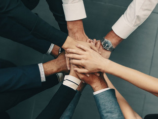 Diverse business team putting their hands together in a huddle of support and motivation