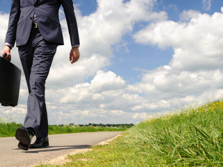 Young businessman walking a pathway in nature with green grass a