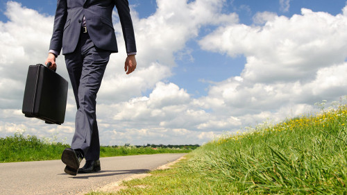 Young businessman walking a pathway in nature with green grass a
