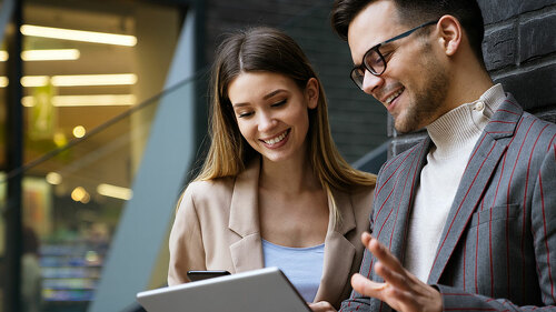 Two creative business people working on social media strategy using a digital tablet