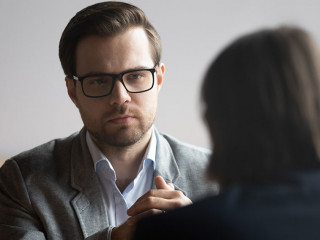 Concentrated male hr manager in glasses listening to job candidate.