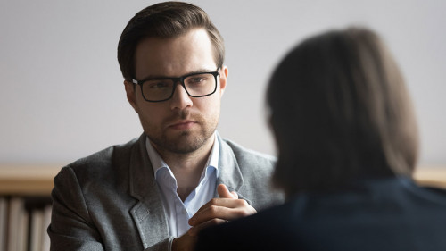 Concentrated male hr manager in glasses listening to job candidate.
