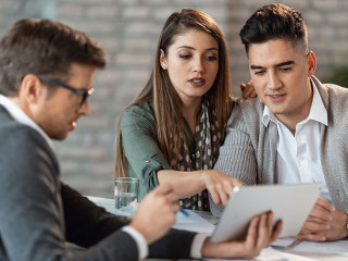 Young couple and financial advisor going through investment plans on digital tablet.