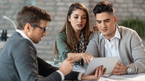 Young couple and financial advisor going through investment plans on digital tablet.