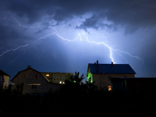 Lightning in the cloudy sky over village
