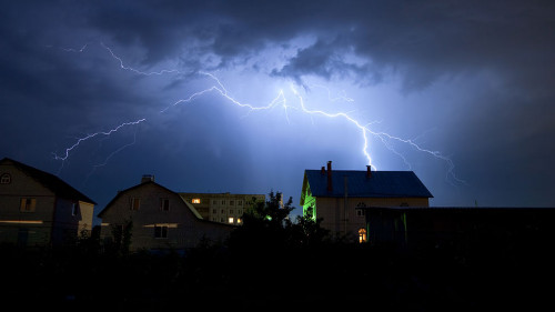 Lightning in the cloudy sky over village