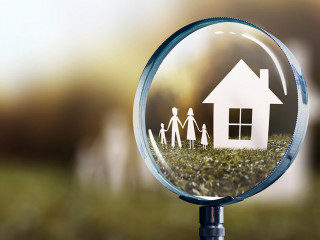 paper house and family focused by a magnifying glass - home buyi