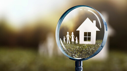 paper house and family focused by a magnifying glass - home buyi