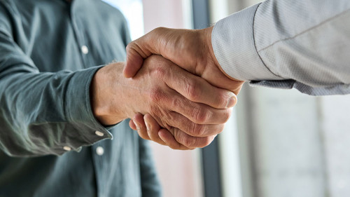Two happy professional businessmen shaking hands at meeting. Handshake