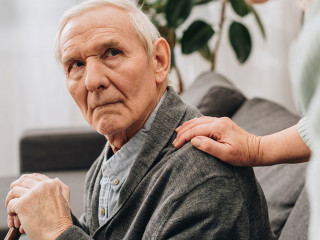 upset retired husband sitting in living room and looking at seni