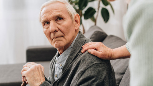 upset retired husband sitting in living room and looking at seni