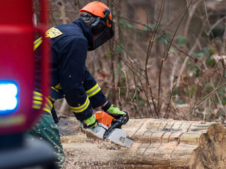 Feuerwehrmann mit Kettensäge beseitigt Sturmschaden