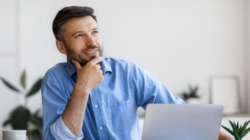 Handsome Male Entrepreneur Sitting At Workplace With Thoughtful Face Expression
