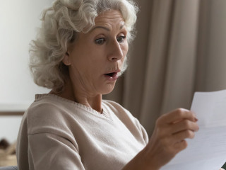 Amazed shocked mature woman with open mouth reading letter