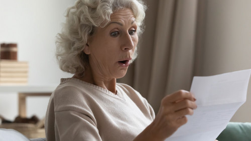 Amazed shocked mature woman with open mouth reading letter