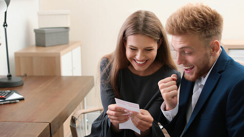 Happy young people with lottery ticket in office