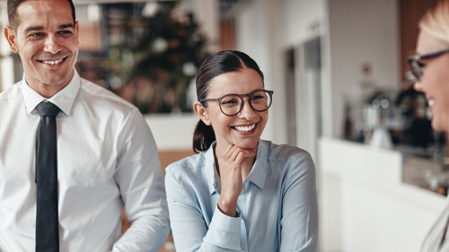 Three smiling coworkers talking together in an office