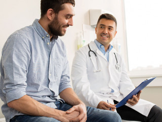 smiling doctor and young man meeting at hospital