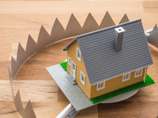 Mortgage house in a trap on wooden table background. House trap