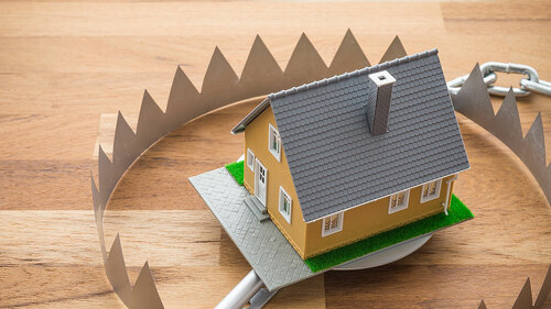 Mortgage house in a trap on wooden table background. House trap