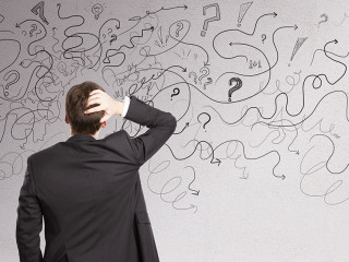 Pensive businessman with abstract arrows sketch on concrete wall background. Confusion and direction concept.
