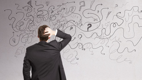 Pensive businessman with abstract arrows sketch on concrete wall background. Confusion and direction concept.