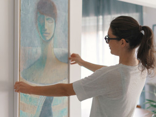 Woman hanging a painting at home