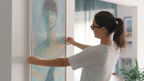 Woman hanging a painting at home