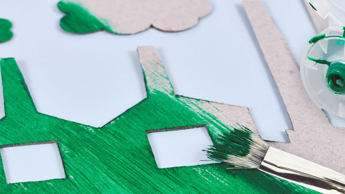 Greenwashing concept with cardboard factory being painted green