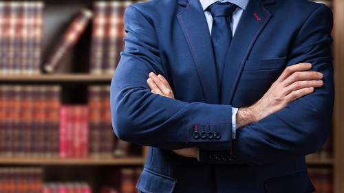 Midsection Of Lawyer Standing Against Bookshelf