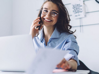 Young woman laughing while talking on cellphone in office