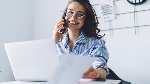Young woman laughing while talking on cellphone in office