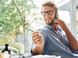Casual young businessman on the phone at desk in office