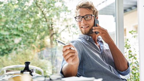 Casual young businessman on the phone at desk in office