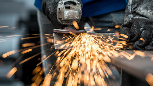 Industrial worker cutting metal with many sharp sparks